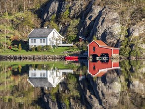 Fjord near Ana Sira at the norwegian southern coast, lonely houses at the foot of a rock formation,