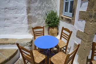 Cosy scene with wooden chairs and a round table in a Mediterranean setting, Chora, main town of