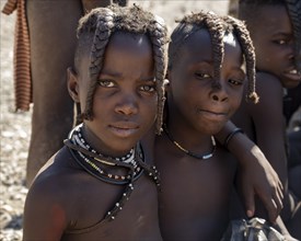 Two Himba girls with braids braided to the front, arm in arm, near Opuwo, Kaokoveld, Kunene,