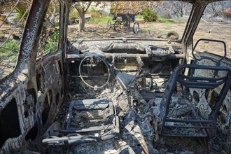 Interior of a burnt car, completely devastated and charred, depicting the utter destruction, forest