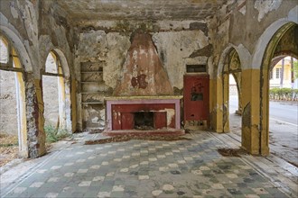 Abandoned room with ruined floor and walls, dilapidated fireplace and arches in a former building,