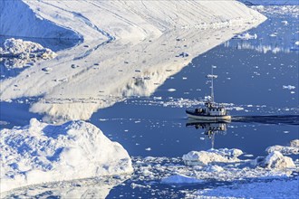 Boat sailing through icebergs and ice floes, reflected in the water, sunny, summer, Jakobshavn