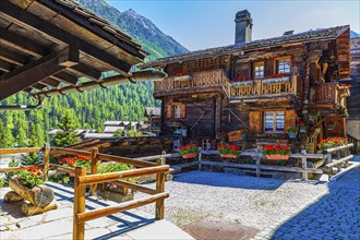 Old wooden house with floral decorations on windows and terrace, historic village centre, Grimentz,