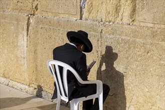 Orthodox jew is praying in front of Sacred Western Wall in Jerusalem Old City Jewish Temple