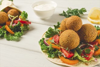 Tortillas, wrapped falafel balls, with fresh vegetables, vegetarian healthy food, on a wooden white