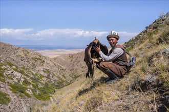 Traditional Kyrgyz eagle hunter with eagle in the mountains, near Kysyl-Suu, Kyrgyzstan, Asia