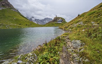 View over the mountain lake Wolayersee to the alpine club hut Wolayerseehütte, cloudy mountain