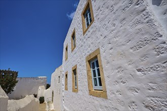 White facade of a historic building with bright windows under a clear blue sky, Simantiris House,