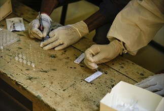 Health worker in personal protective equipment (PPE) collects a nasal swab sample from locals for