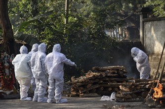 Family members wearing PPE kit performing last rites of a person who died of COVID-19 coronavirus