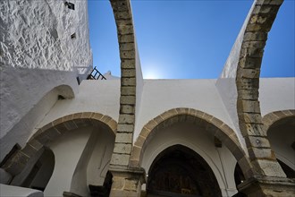 Medieval architecture with stone arches and white walls under a clear blue sky, Agiou Theologou