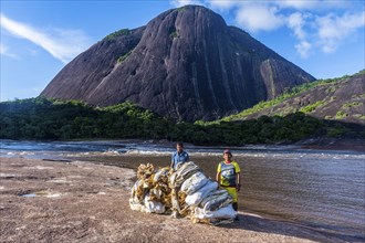 Fisherman with their fish before the huge granite hills, Cerros de Mavecure, Eastern Colombia