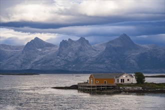 Boathouse on the shore, the Seven Sisters mountain range behind, Heroy island, Helgeland coast,