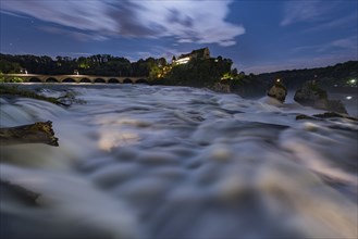 The Rhine Falls with Laufen Castle and the railway bridge at night, waterfall in Neuhausen am