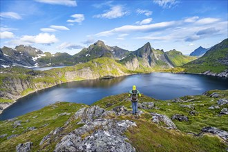 Mountaineer looking over lake, mountain landscape with lake Tennesvatnet, at sunrise, behind peak