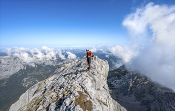 Mountaineer on a rocky narrow mountain path with mountain panorama, mountain tour to the summit of