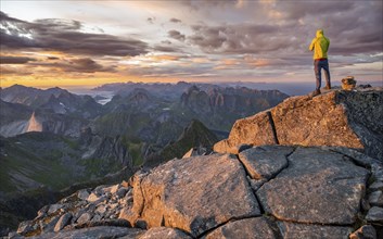 View over mountain top and sea, dramatic sunset, climbers at the top of Hermannsdalstinden,