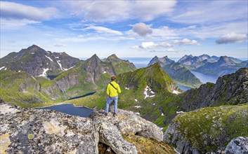 Mountaineer at the summit of Munken, mountain landscape with steep rocky peaks, lakes FJorde and