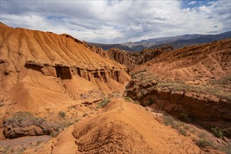 Eroded mountain landscape with sandstone cliffs, canyon with red and orange rock formations,