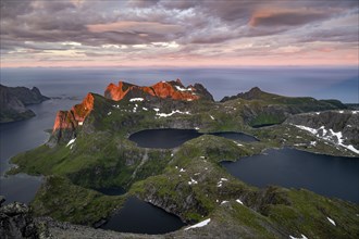 View over mountain peaks and sea, dramatic sunset, from Hermannsdalstinden, with lakes