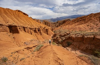 Mountaineer on a mountain ridge, view of eroded mountain landscape with sandstone cliffs, canyon