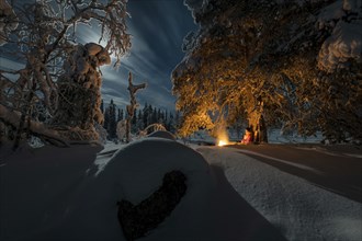 Man in the evening at a bivouac with campfire, Lapland, Sweden, Scandinavia, Europe