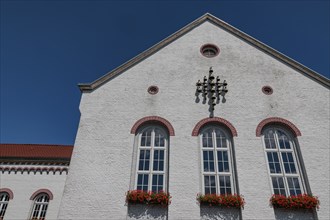 A building with a white wall and windows with flowers in front of it under a blue sky, Xanten,