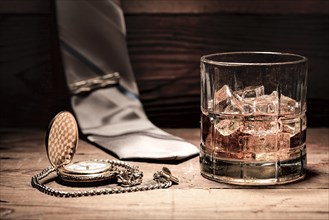 A conceptual image of aa glass of liquor, a pocket watch, and a neck tie