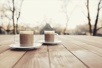 Two cups of coffee in the wooden brown terrace background.