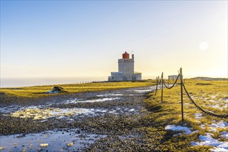 Trail leading to the famous lighthouse at sunset on Dyrholaey beach in Iceland in the cold winter,