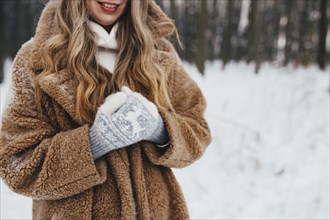 Young woman in fur coat, gloves and scarf in snowy forest.