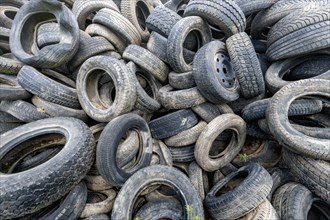 Old broken car tyres piled up up to form a mountain as a background