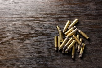 Empty bullet casings on a dark, wooden table