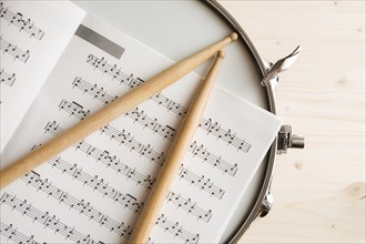 Music score drumsticks and drum tuner over a snare drum with wooden background