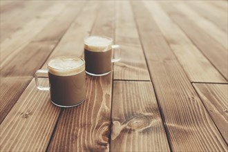 Two cups of coffee in the wooden brown terrace background.