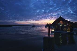 From the harbor in zingst the bodden view with burning sky with house. dynamic clouds in full color