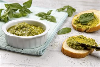 A photo of spreading fresh pesto on small slices of bread in a studio setting