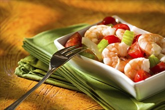 Close up of shrimp salad with squid tomatoes celery inside a white bowl