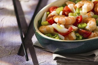 Close up of salad of shrimps and chopsticks inside an oval bowl