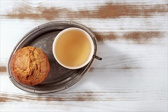 Orange muffin with tea on a rustic wooden kitchen table, on a vintage tray, overhead flat lay shot