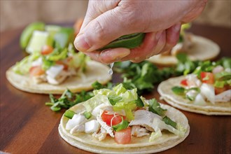 Squeezing lime juice on a finished street taco in a studio setting