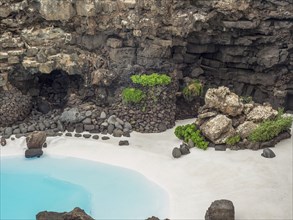 A rocky cave landscape with blue water and white sand, Lanzarote, Canary Islands, Spain, Europe