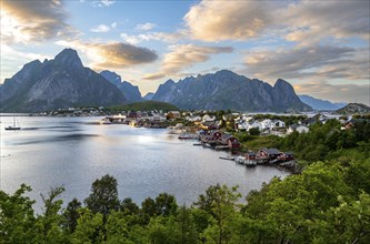 Village view of the fishing village Reine, traditional red Rorbuer cabins, at sunset, in the back