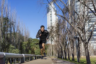 Runner athlete silhouette running fast in public park. Copy space