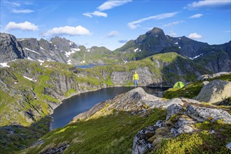 Mountaineer standing on a rock with green camping tent, mountain landscape with lake Tennesvatnet,