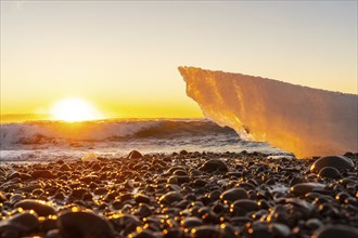 The sun rises at dawn on Diamond Beach next to Jokulsarlon in winter in Iceland