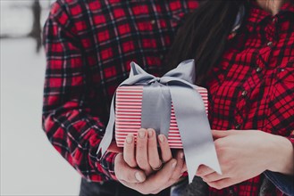 Boyfriend giving a gift box present with ribbon outdoor due to Saint Valentine day to her