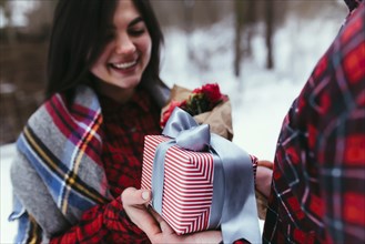 Hands giving a gift box with ribbon. Blurred background.