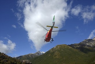 ARTHURS PASS, NEW ZEALAND, 2021-01-29: A brightly painted helicopter takes off from a car park in