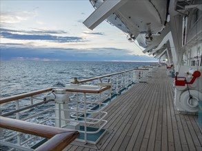 Wooden deck of a ship with a view of the calm, wide sea and the cloudy sky at sunset, svaneke,